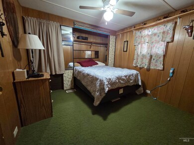 Bedroom featuring carpet flooring, wooden walls, and ceiling fan