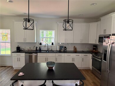 Kitchen with stainless steel appliances, a sink, light wood-style floors, dark countertops, and recessed lighting