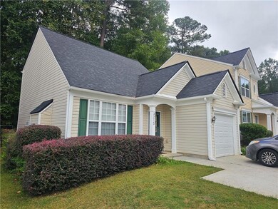 Traditional-style home featuring roof with shingles, an attached garage, a front lawn, and concrete driveway