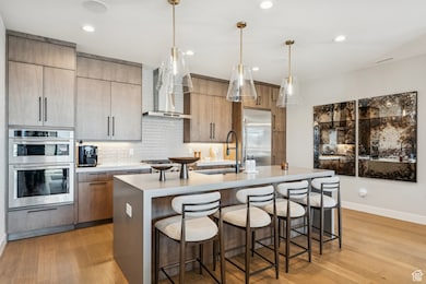Kitchen featuring decorative light fixtures, modern cabinets, a breakfast bar area, light stone countertops, and recessed lighting