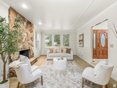 Living room with crown molding, carpet flooring, a stone fireplace, and recessed lighting