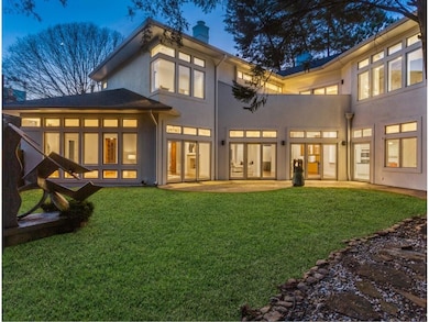 Rear view of property featuring a chimney, stucco siding, and a yard