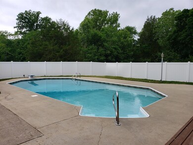 Fenced in ground pool with concrete patio.