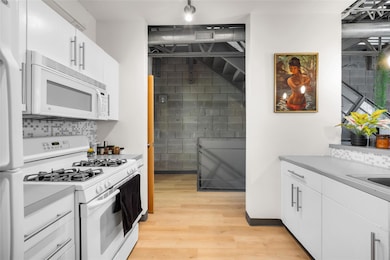 Kitchen with white cabinetry, white appliances, a