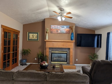 Living area with a textured ceiling, a high end fireplace, vaulted ceiling, french doors, and ceiling fan