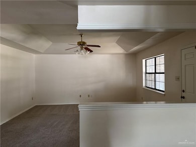 Unfurnished room featuring a tray ceiling, dark colored carpet, ceiling fan, and lofted ceiling