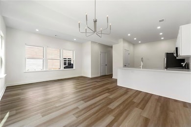 Unfurnished living room featuring a chandelier, light wood-style floors, and recessed lighting