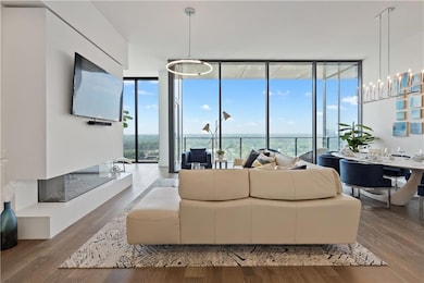 Dining space with a wall of windows, wood finished floors, and a chandelier