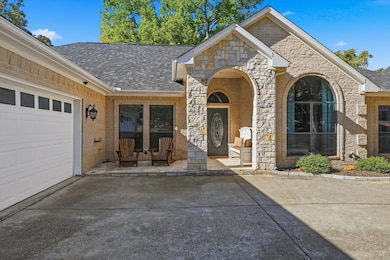 Doorway to property with stone siding, roof with shingles, brick siding, and a garage