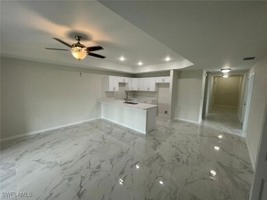 Kitchen with a peninsula, a sink, baseboards, a tr