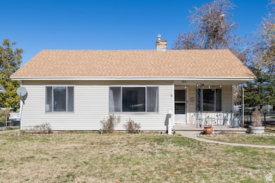 View of front of house with a porch, roof with shingles, and a chimney