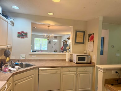 Kitchen with white appliances, white cabinetry, light countertops, hanging light fixtures, and a chandelier