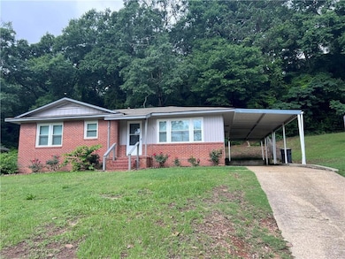View of front of property featuring concrete driveway, a front yard, brick siding, and a carport