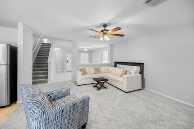 Living room with stairs, ceiling fan, and light c