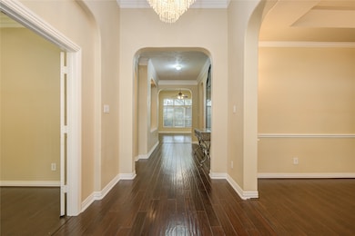 The welcoming front entry with chandelier is open to the study and dining room with wide hallway looking towards the family room.