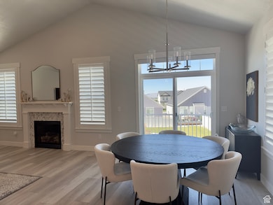 Dining space featuring a tiled fireplace, vaulted ceiling, and light wood-style flooring