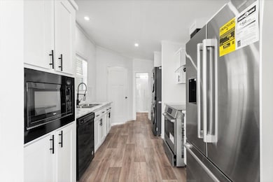 Kitchen featuring black appliances, light wood-st
