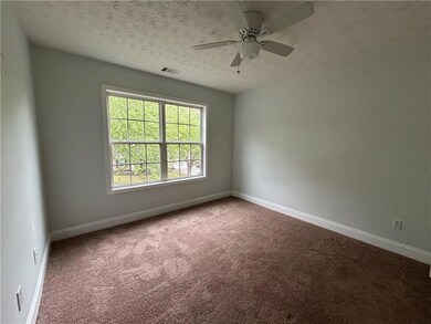 Carpeted spare room featuring a textured ceiling, baseboards, and a ceiling fan