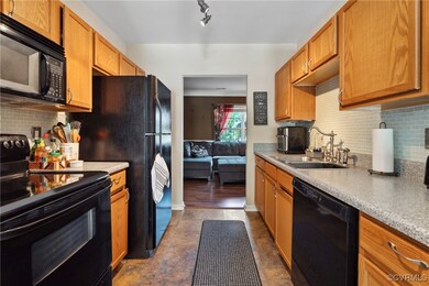 Kitchen featuring black appliances, tasteful backsplash, sink, and track lighting