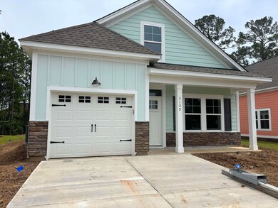 View of front of house with a shingled roof, stone siding, driveway, covered porch, and board and batten siding