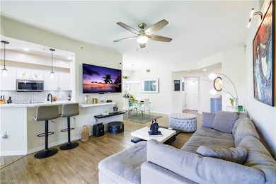 Living area with ceiling fan, wood finished floors, and recessed lighting