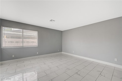 Unfurnished room featuring marble look tile flooring and baseboards