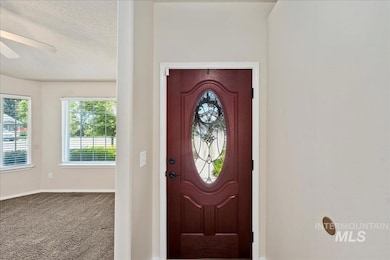 Carpeted foyer featuring ceiling fan and a textured ceiling