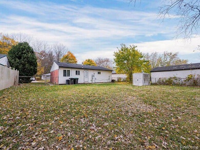 Rear view of property featuring a fenced backyard and a storage unit