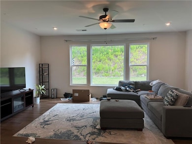 Living room with healthy amount of natural light, ceiling fan, and wood finished floors