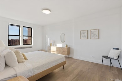 Bedroom with radiator heating unit and light wood-type flooring