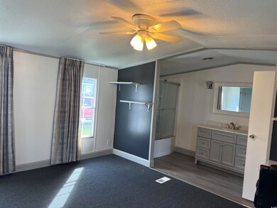 Unfurnished bedroom with a sink, a textured ceiling, lofted ceiling, baseboards, and a ceiling fan