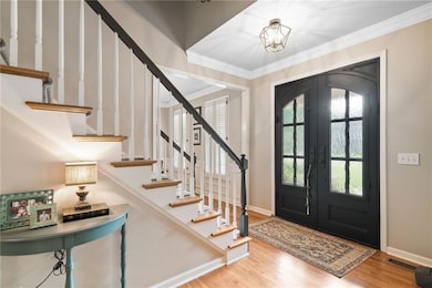 Entryway with ornamental molding, french doors, wood finished floors, baseboards, and stairs