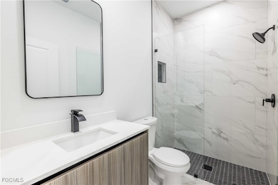 Bathroom featuring vanity and a marble finish shower