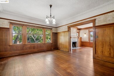 Unfurnished living room featuring a chandelier, hardwood / wood-style flooring, a textured ceiling, ornamental molding, and wood walls