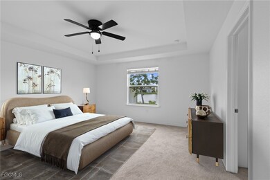 Carpeted bedroom featuring a raised ceiling and ceiling fan