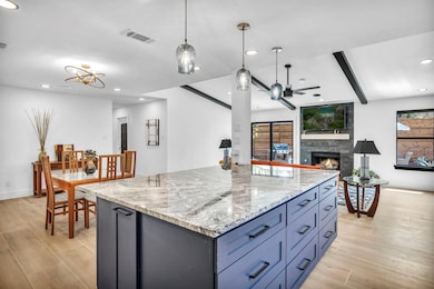 Kitchen featuring a center island, a fireplace, light wood-type flooring, hanging light fixtures, and recessed lighting
