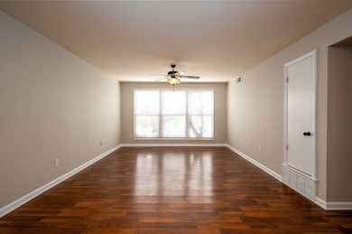 Empty room featuring ceiling fan and dark hardwood