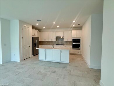 Kitchen layout with alternate kitchen island, stainless steel appliances, quartz countertops, and wood cabinets