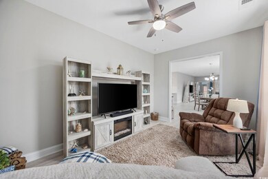 Living room with ceiling fan with notable chandelier and light hardwood / wood-style floors