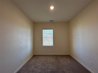 Spare room featuring dark colored carpet and baseboards
