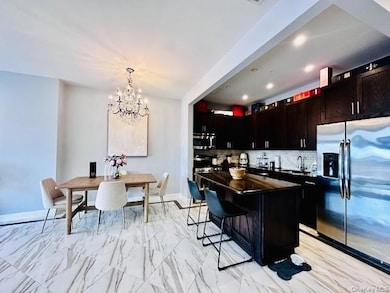 Kitchen featuring stainless steel appliances, decorative backsplash, hanging light fixtures, an island with storage, and a chandelier