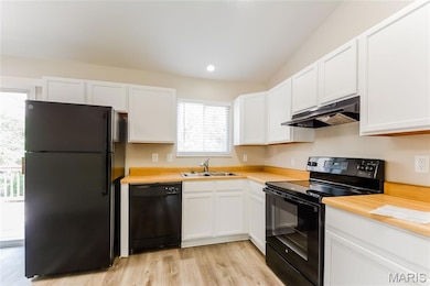 Kitchen featuring black appliances, light countertops, under cabinet range hood, light wood-style floors, and white cabinets