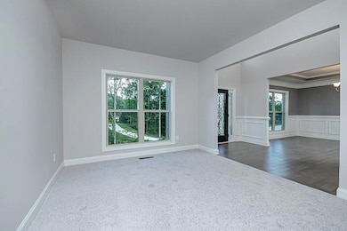 Spare room featuring visible vents, baseboards, dark carpet, dark wood-style floors, and a wainscoted wall