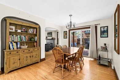Dining area with arched walkways, a chandelier, a brick fireplace, light wood-type flooring, and baseboards