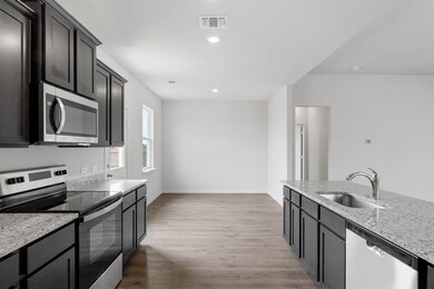 Kitchen with appliances with stainless steel finishes, light stone countertops, light wood-style floors, recessed lighting, and dark cabinetry