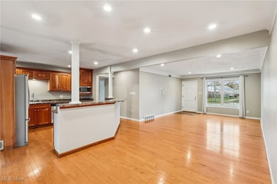 Kitchen featuring light wood-style flooring, recessed lighting, brown cabinetry, appliances with stainless steel finishes, and a kitchen island