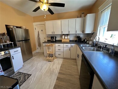 Kitchen with appliances with stainless steel finishes, ceiling fan, white cabinets, sink, and backsplash