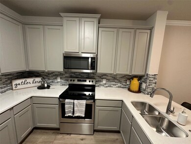 Kitchen featuring gray cabinetry, backsplash, stainless steel appliances, crown molding, and sink