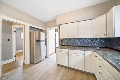 Kitchen featuring stainless steel fridge, white cabinetry, and backsplash