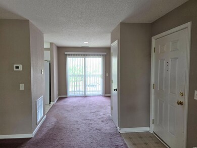 Corridor with a textured ceiling, baseboards, and light colored carpet
